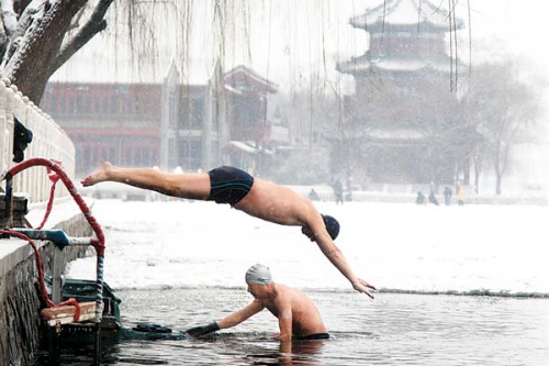 The freezing water in Houhai, Beijing, does not deter swimmers from diving in on Sunday. Many parts of northern China were blanketed in snow over the weekend. [Photo by Han Haidan / For China Daily]