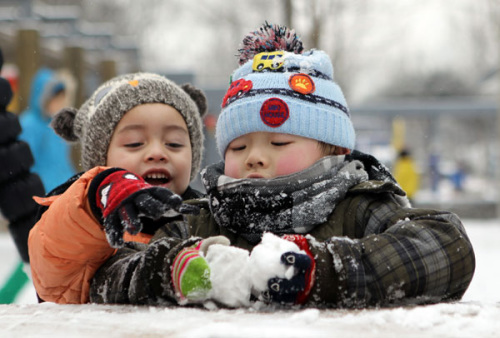 Children make snowballs in Beijing on Sunday. The snow, that fell in most parts of northern China over the weekend, will continue on Monday. [Photo/GUAN XIN / CHINA DAILY]