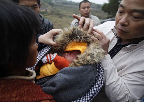 A woman holding a baby boy she bought from child traffickers is stopped by plainclothes police officers in Anxi county, Quanzhou, Fujian province, in December. [China Daily] 