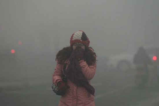 A woman covers her nose when walking through dense fog in Beijing on Tuesday. [Bai Jikai / for China Daily] 