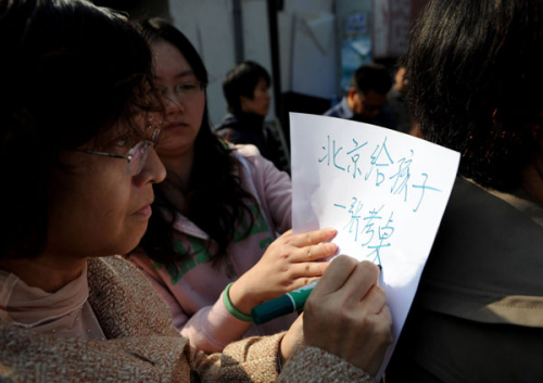 A mother asks for her child to have the right to take the national college entrance examination in Beijing. Parents of migrant children without Beijing hukou gather at the gate of the capital's education commission to check for updates of the gaokao rules