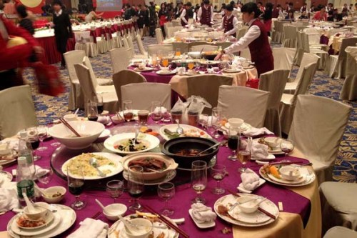 Waitresses clear tables, where plenty of food was left over, after a dinner for staff members from a State-owned enterprise at a five-star hotel in Guangzhou, Guangdong province, on Sunday. The dinner included more than 70 tables at a cost of 3,900 yuan ($627) per table. [Photo/Xinhua]