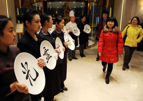 Staff members hold plates, encouraging diners to finish their meals, at the entrance to the Qingdao Seaview Garden Hotel in Shandong province on Thursday. [Photo/Xinhua]