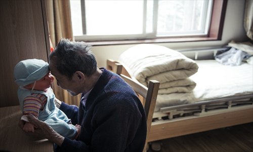 An elderly man plays with a doll at Cuncao Chunhui nursing home in Chaoyang district Monday. Photo: Li Hao/GT 