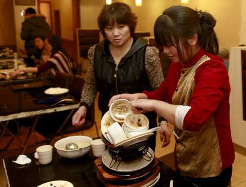 Servers clean plates at a restaurant in Beijing on Tuesday. The recent appeal to fight against extravagance has helped reduce the amount of waste at restaurants. [Feng Yongbin / China Daily]