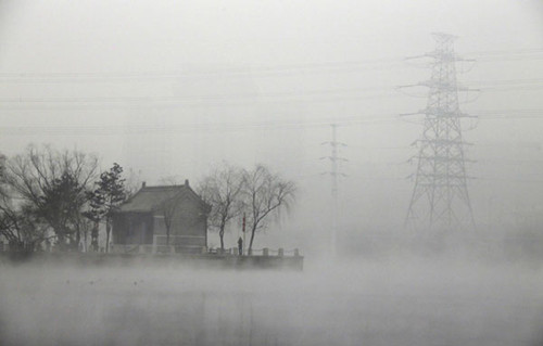 A man fishes near a temple beside a river on a heavy hazy day during winter in Beijing's Gaobeidian village, January 30, 2013. [Photo/Agencies]