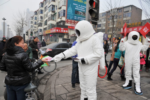 A man dressed as an astronaut hands out free masks on a street in Taiyuan city of North China's Shanxi province C one of China's coal mine hubs - on Jan 31, 2013. [Photo by Liu Jiang/Asianewsphoto]