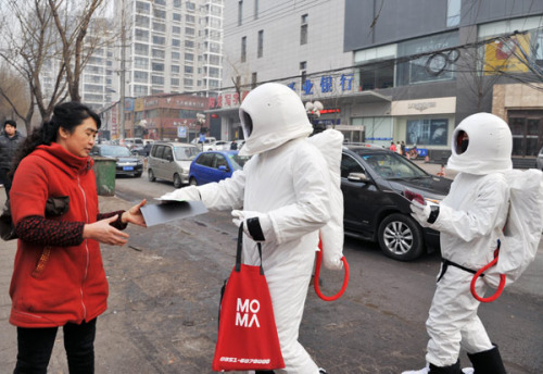 A man dressed as an astronaut hands out free masks on a street in Taiyuan city of North China's Shanxi province �C one of China's coal mine hubs - on Jan 31, 2013. [Photo by Liu Jiang/Asianewsphoto]