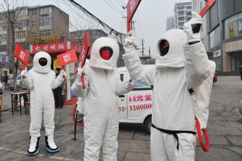 Men dressed as astronauts hand out masks in Taiyuan city of North China's Shanxi province C one of China's coal mine hubs - on Jan 31, 2013. [Photo by Liu Jiang/Asianewsphoto]