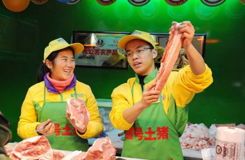 Hao Chengbin (R), a graduate from Jiangxi University of Finance and Economics, and Sun Xia (L), a graduate from University of Hainan, promote pork to a customer at a No.1 Soil Pig butcher shop in Shanghai on Jan. 29, 2013. (Photo/CNS)