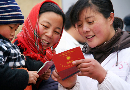 A staff member (right) at a village clinic in Shandong province explains the rural cooperative medical program to a resident. The program now covers 900 million people across the country. [ZHANG CHUNLEI / FOR CHINA DAILY]