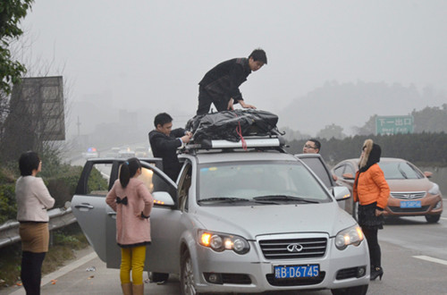 Travelers check their luggage on an expressway in Hunan province on Saturday. They all work in Guangzhou, Guangdong province, and shared a car to return to their homes in Huaihua, Hunan province, for Spring Festival. [China Daily]