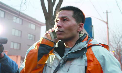 Zhu Ruifeng picks up a phone for an interview with a foreign reporter outside the Dewai police station in Beijing on January 28, after walking out of a seven-hour negotiation session with Chongqing police. Photo: Chang Meng/GT 