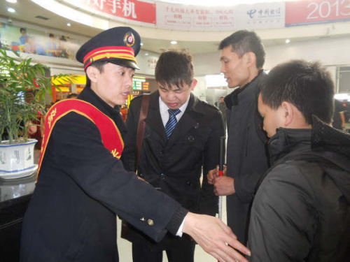 Zhang Yun (left) helps three blind men board a train bound for Nanchong in Sichuan province on Monday. [HUANG ZHILING / CHINA DAILY]