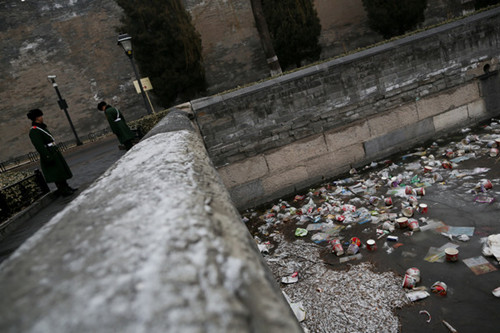 Litter dropped by tourists, mostly plastic packaging, dots the surface of the moat surrounding the Forbidden City in Beijing. It is diffi cult to clear the trash as the moat is half-frozen. [CHINA DAILY]