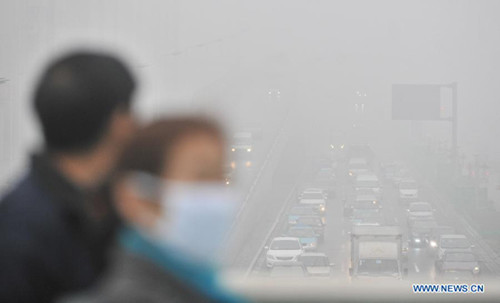 Citizens wearing masks walk amid fog and smog in Tianjin, north China, Feb. 28, 2013. The fog hit Tianjin on Feb. 28 morning, causing heavy air pollution in the city. [Xinhua]