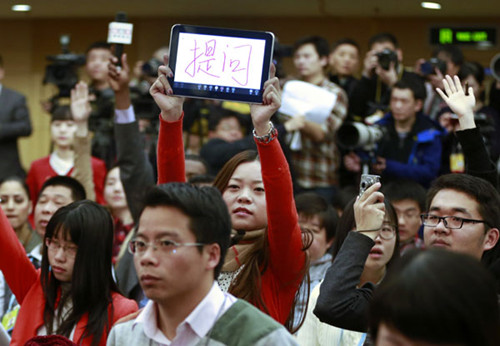 A journalist raises a computer tablet reading I have a question, at a news conference on people's livelihood and social services during the first session of the 12th National People's Congress in Beijing on Wednesday. Feng Yongbin / China Daily