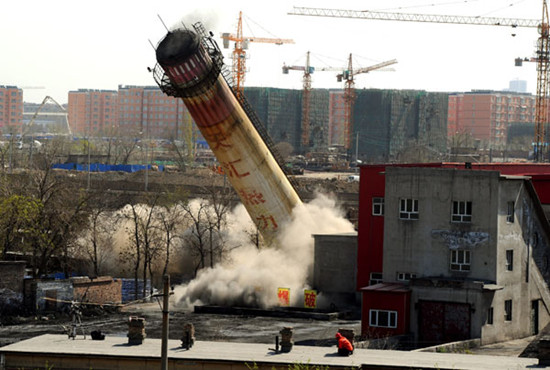 A 30-meter-high chimney of a coal-fired boiler is toppled in Urumqi, capital of the Xinjiang Uygur autonomous region, in April 2012. JIANG WENYAO / XINHUA