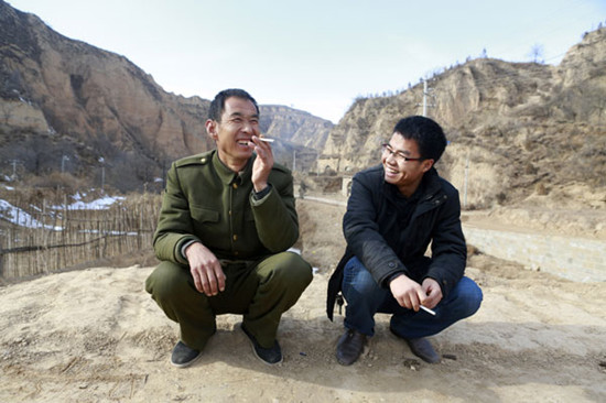 Zhang Qiang (right) talks with a resident of Liangjiahe village in Shaanxi province. Zhang is one of 300,000 college graduates who have become village officials since China launched a nationwide program in 2009. He is now assistant to the village Party chief. Feng Yongbin / China Daily