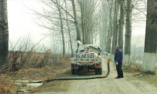 A man pours an unknown green-colored liquid from a tanker truck into a drain that lets out into a waterway in Changping district Sunday. Photo: Courtesy of Zhang Yi 