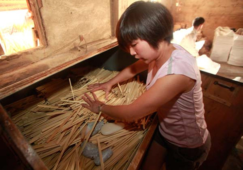 A worker at a chopstick factory shows how to polish disposable chopsticks with toxic paraffin wax and talc in Liuzhou, the Guangxi Zhuang autonomous region, in April. [Photo/Xinhua]