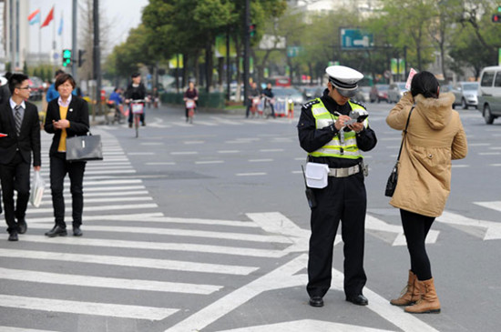 A pedestrian is fined 5 yuan for jaywalking in Hangzhou city, Zhejiang province on March 21. [Photo/Xinhua]