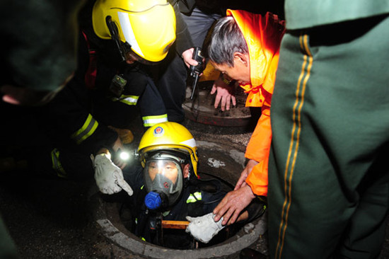 A rescue worker in Changsha, Hunan province, enters a sewer on Sunday to search for a woman who had fallen in during heavy rain on Friday. GUO LILIANG / FOR CHINA DAILY 
