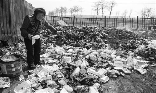 A resident picks through a smoking garbage pile in Shicao village, Chaoyang district Monday. Photo: Li Hao/GT