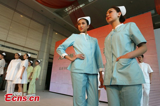 Two women display uniforms for nurse in Beijing, April 1, 2013. Beijing is planning to change hospital uniforms for doctors, nurses, logistics workers and patients. (CNS photo)