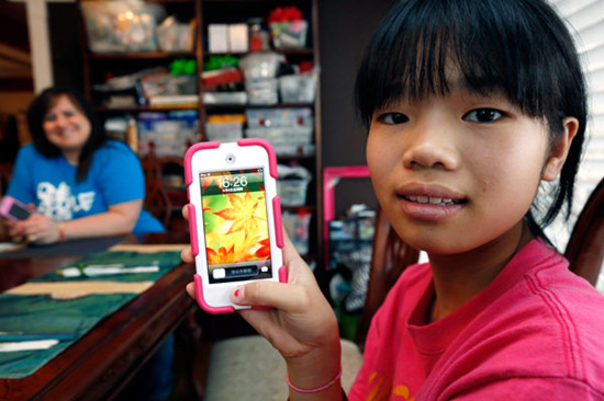 Guan Ya Smith, 14, who is deaf, shows off her iPod that allows her to communicate with her new adoptive family through Google Translate. Phillip and Niki Smith (background) and their three other children in Rienzi, Mississippi, use the program to speak with Guan Ya. Rogelio V. Solis / Associated Press