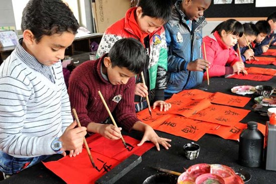 Pupils whose parents are foreigners write Spring Festival couplets with their classmates in Wu'ai Primary School in Yiwu, Zhejiang province, in January. About 500 children of expats live and receive education in the city. Zhang Jiancheng / China Daily 