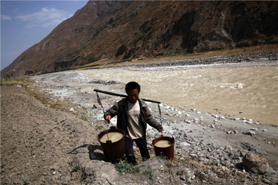 A villager fetches water from the polluted river after the water supply for his home has been cut for half a month in Kunming, Yunnan province on March 20, 2013. [Photo by Guo Tieliu/ Asianewsphoto]