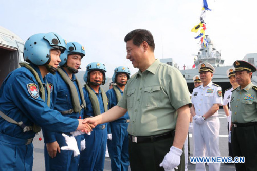 Chinese President Xi Jinping, who is also the general secretary of the Communist Party of China (CPC) Central Committee and chairman of the Central Military Commission, shakes hands with shipboard helicopter pilots on vessel Jinggangshan, in Sanya, south 