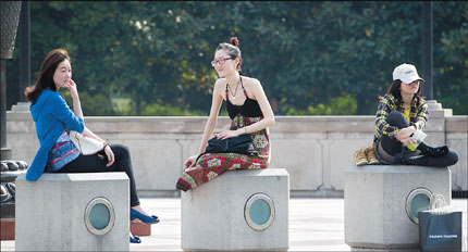 Three women have no need for heavy coats as they sit by a fountain in People's Square yesterday, as the mercury surged to 26 degrees Celsius. 