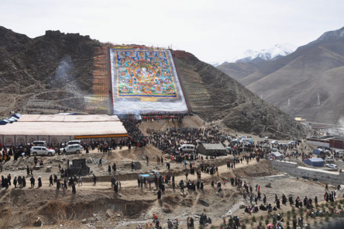 A gigantic thangka, or silk painting, is spread over a hillside during a Buddhist commemoration on Sunday marking the third anniversary of the magnitude-7.1 Yushu earthquake. [Photo/CNS]
