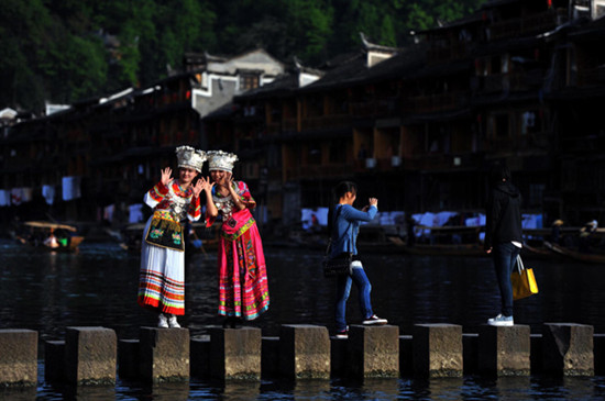 People pose for photos in Fenghuang county, Hunan provincem April 13, 2013. [Photo/Xinhua]