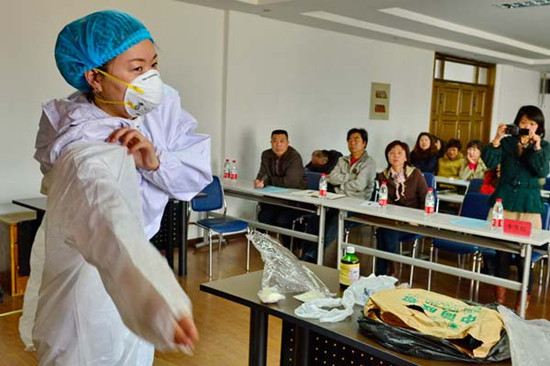 A medical worker in Qinhuangdao, Hebei province, demonstrates how to use a protection suit against the bird flu virus on Wednesday. LIU XUEZHONG / FOR CHINA DAILY 