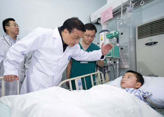 Premier Li Keqiang consoles a young earthquake victim in a hospital in Chengdu on Sunday. [Photo/Xinhua]
