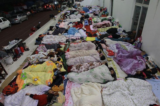 Quake survivors sleep in the open air at a temporary shelter set up at the stadium of Baoxing County New High School on Monday night because the shelter does not have enough tents. Cui Meng / China Daily