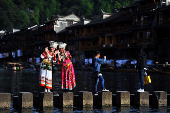 Tourists pose for photos in ethnic clothes in the scenic old town of Fenghuang, Hunan province. The town recently began to charge tourists an entrance fee, which sparked a huge debate and a protest from local vendors. Zhao Zhongzhi / Xinhua
