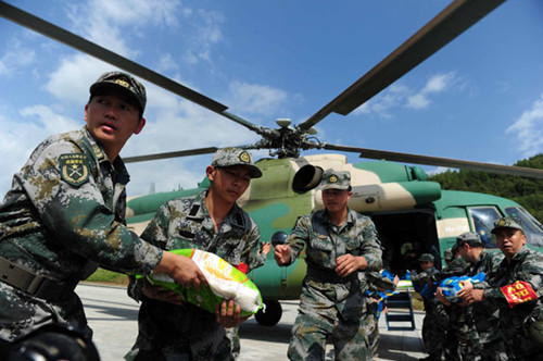 Soldiers from the Chengdu Military Command Area load a bag of rice onto a helicopter heading to quake-hit areas in Lushan, Sichuan province, on Wednesday. GUO LILIANG / FOR CHINA DAILY