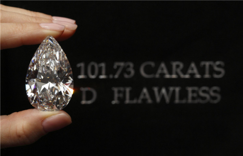 A Christie's member of staff displays a pear-shaped, D color, flawless diamond of 101.73 carats during an auction preview in Geneva, April 30, 2013. [Photo: China Daily/Agencies]