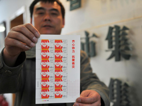 A man shows a set of stamps themed by Lushan earthquake in Jinan city, East China's Shandong province on May 2, 2013. [Photo/Xinhua]