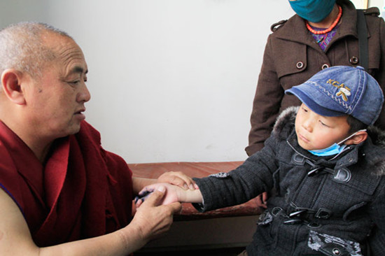 Monk-doctor Ngawang Lhundrup, who has practiced for 39 years, checks the pulse of a child. Wang Huazhong / China Daily