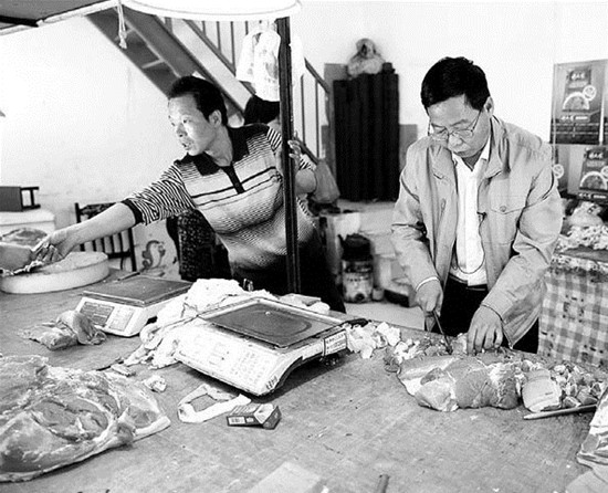 Lu Buxuan (right) helps his brother Lu Buning in the family butcher's shop. Chen Tuanjie / For China Daily