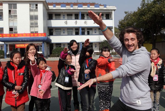 A foreign teacher at Hailiang International School in Zhuji, Zhejiang province, interacts with pupils from a primary school for migrant workers in the city's Taozhu street on March 4. Photo by Luo Shanxin / for China Daily