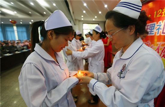New graduates attend a capping ceremony at a nurses' school in Huaibei, Anhui province, on Thursday. About 100 representatives vowed to carry forward the Florence Nightingale spirit and to serve patients wholeheartedly. The ceremony was held to mark the International Nurse Day on May 12. Wan Shanchao / for China Daily
