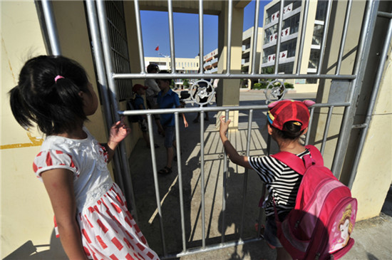Pupils stand outside Wanning No 2 Primary School in Hainan province, whose principal has been charged with sexual assaults on minors. [Photo by Hai Nan / for China Daily]