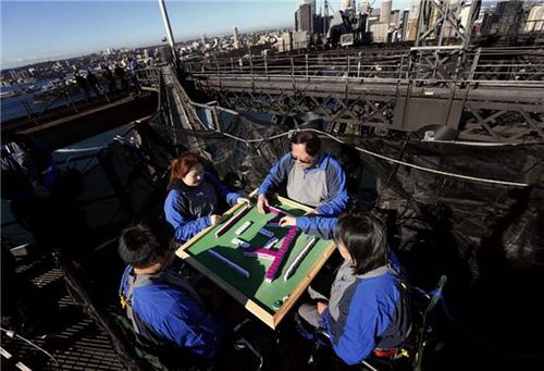 Tony Liu, Ling Khor, Jak Heng and Pauline Heng wave as they play the traditional Chinese board game 'mahjong' on top of the Sydney Harbour Bridge during a  promotional event in Sydney May 15, 2013, in this picture provided by Bridgeclimb. Sitting 134 metres above sea level, the game was held to promote The Mandarin Climb tours during which visitors can climb to the top of the iconic bridge with the assistance of Mandarin-speaking guides. Sydney will also host the World Series of Mahjong from June 2 to 4. [Photo/Agencies] 