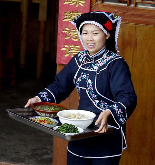 A Bouyei woman serves local food to visitors in Wanggang village in Guiyang. Photo by Feng Yongbin / china daily